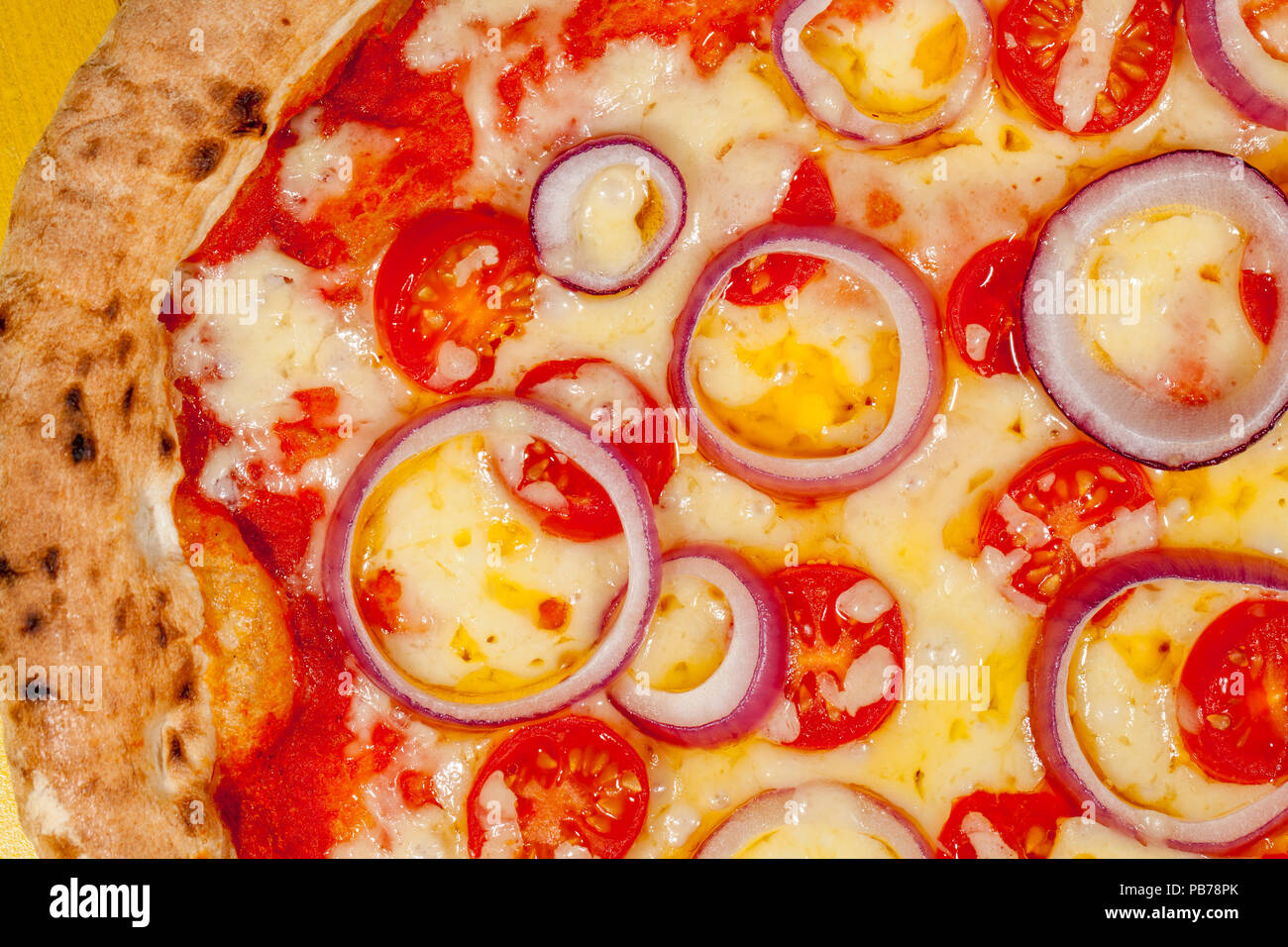 Hot pizza close-up. Cheese onion and tomato on scorched sourdough base. Classic Italian comfort food. Stock Photo
