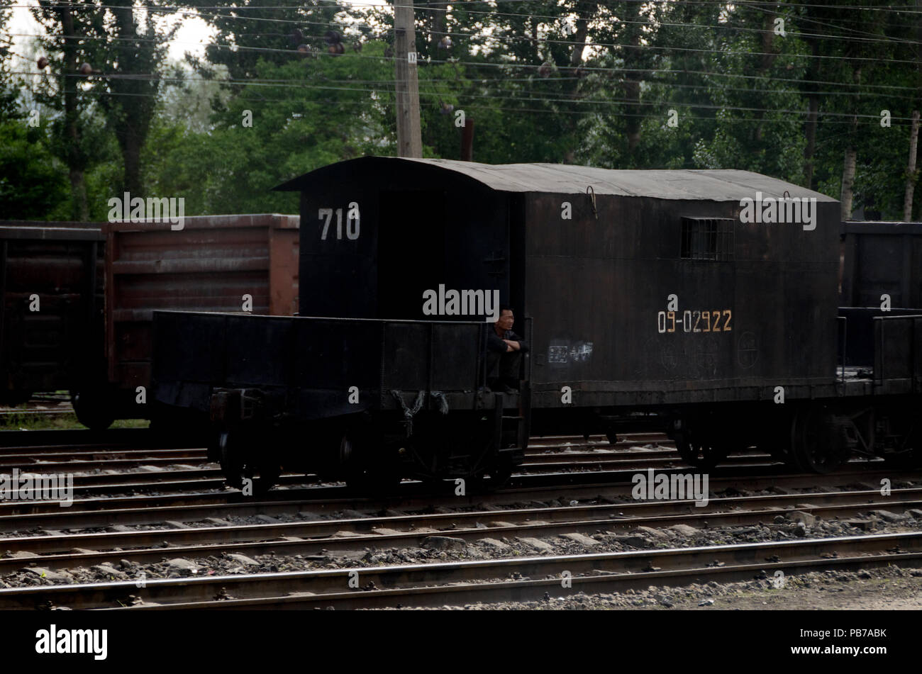 Korean worker sitting on the step of a rail carriage, North Korea Stock Photo