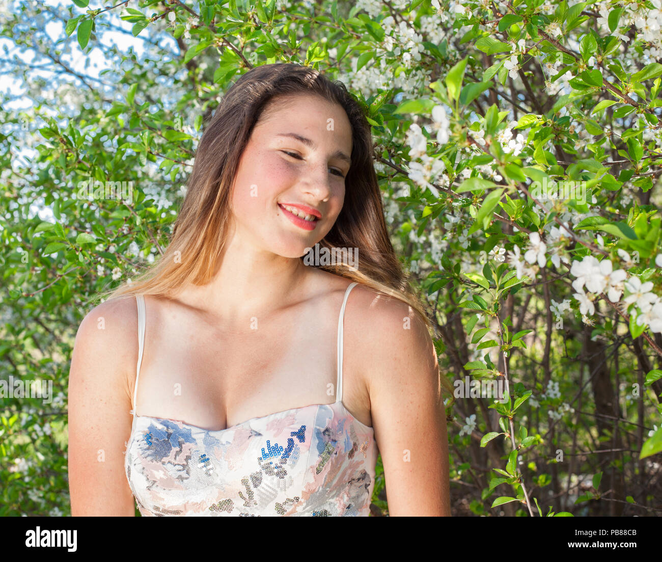 beautiful girl in a summer dress surrounded by a blossoming tree close-up portrait Stock Photo