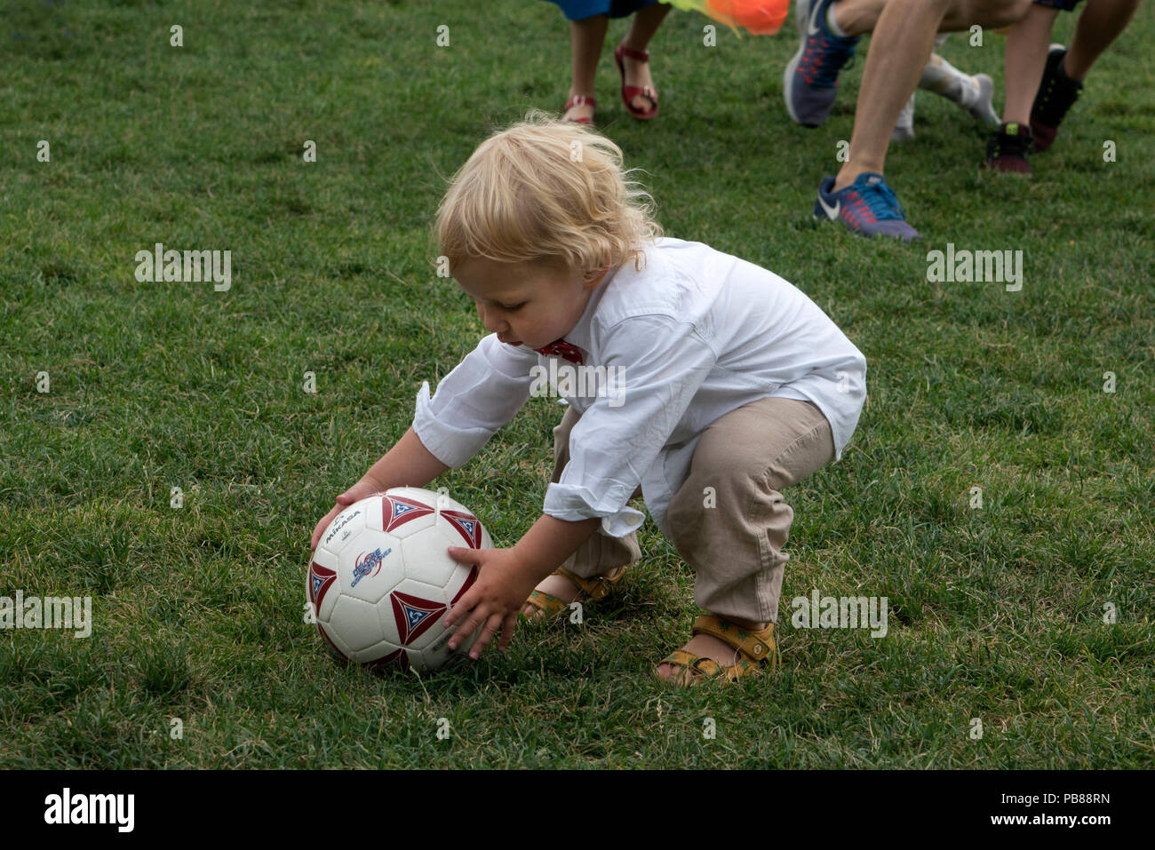 A boy picking up a soccer ball during the Swedish Midsummer Festival in Battery Park City. Stock Photo