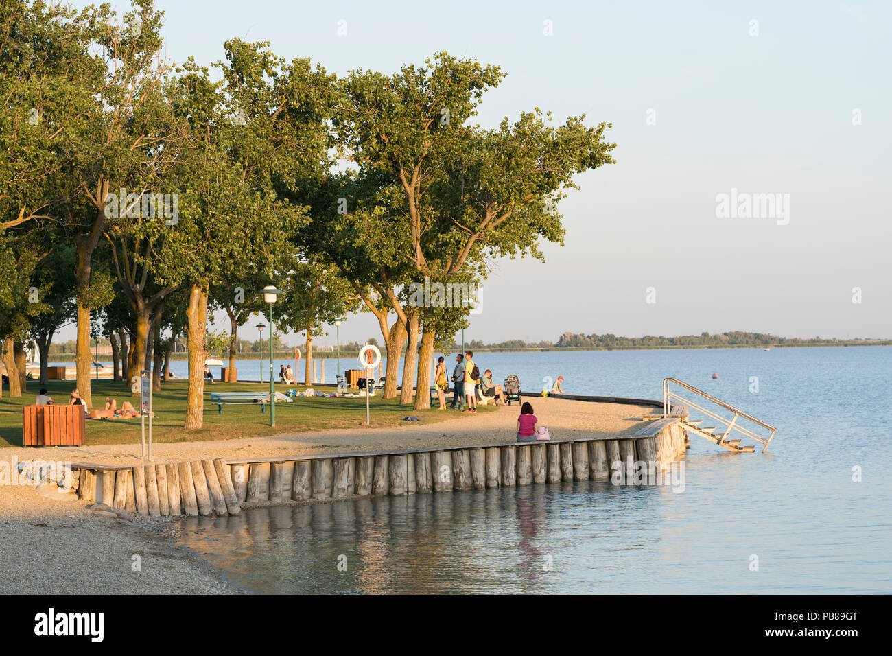 Tourists sunbathing and strolling in a park next to Neusiedler See on a summer's evening in Neusiedl am See, Burgenland Stock Photo