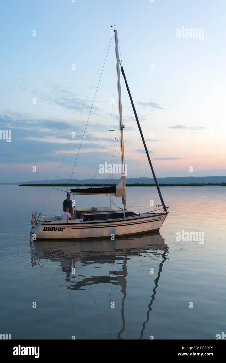 A sailing boat sailing off into the sunset on a summer's night on the