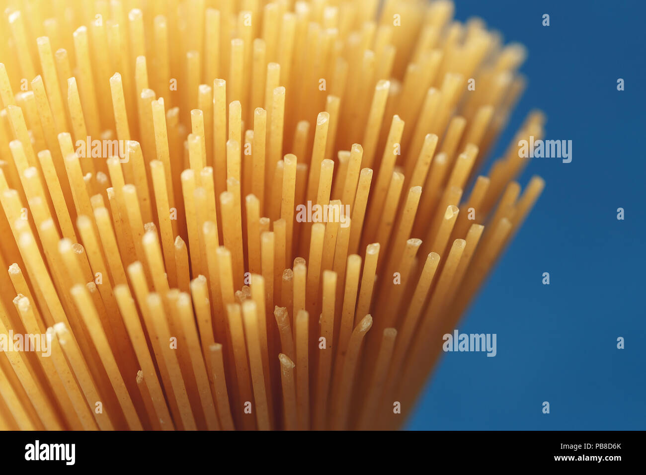 Bunch of uncooked Italian pasta spaghetti on a blue background. Macro ...