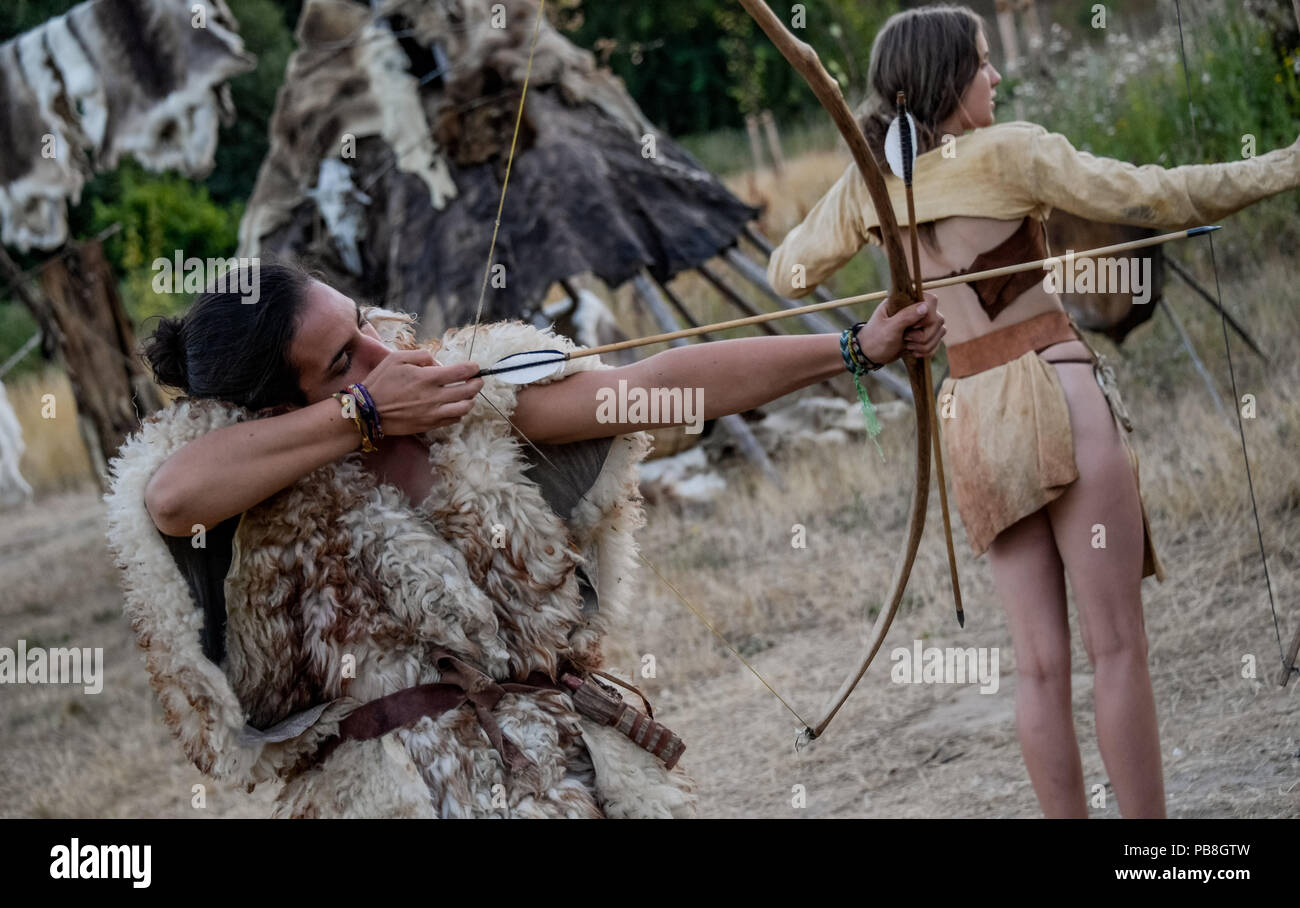Albersdorf, Germany. 24th July, 2018. Two women practice archery with a self-made bow. Around 80 men, women and children met in Alberdorf in the district of Dithmarschen under the motto 'largest Stone Age meeting since the Stone Age'. Credit: Axel Heimken/dpa/Alamy Live News Stock Photo