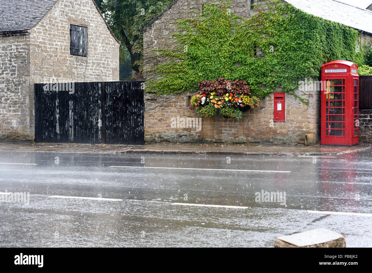 Linby, Nottinghamshire, UK. 27th July 2018: After over two months with very little rain parts of the East Midlands are seeing heavy downpours and thunderstorms this morning. Rain flows along Main street in Linby village. Credit: Ian Francis/Alamy Live News Stock Photo