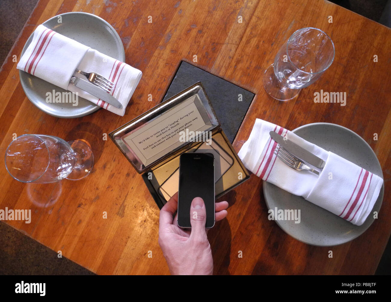 New York, USA. 26th Oct, 2017. A guest places his mobile phone in a special  box in the Hearth Restaurant. The owner of the restaurant would like to  encourage his guests to