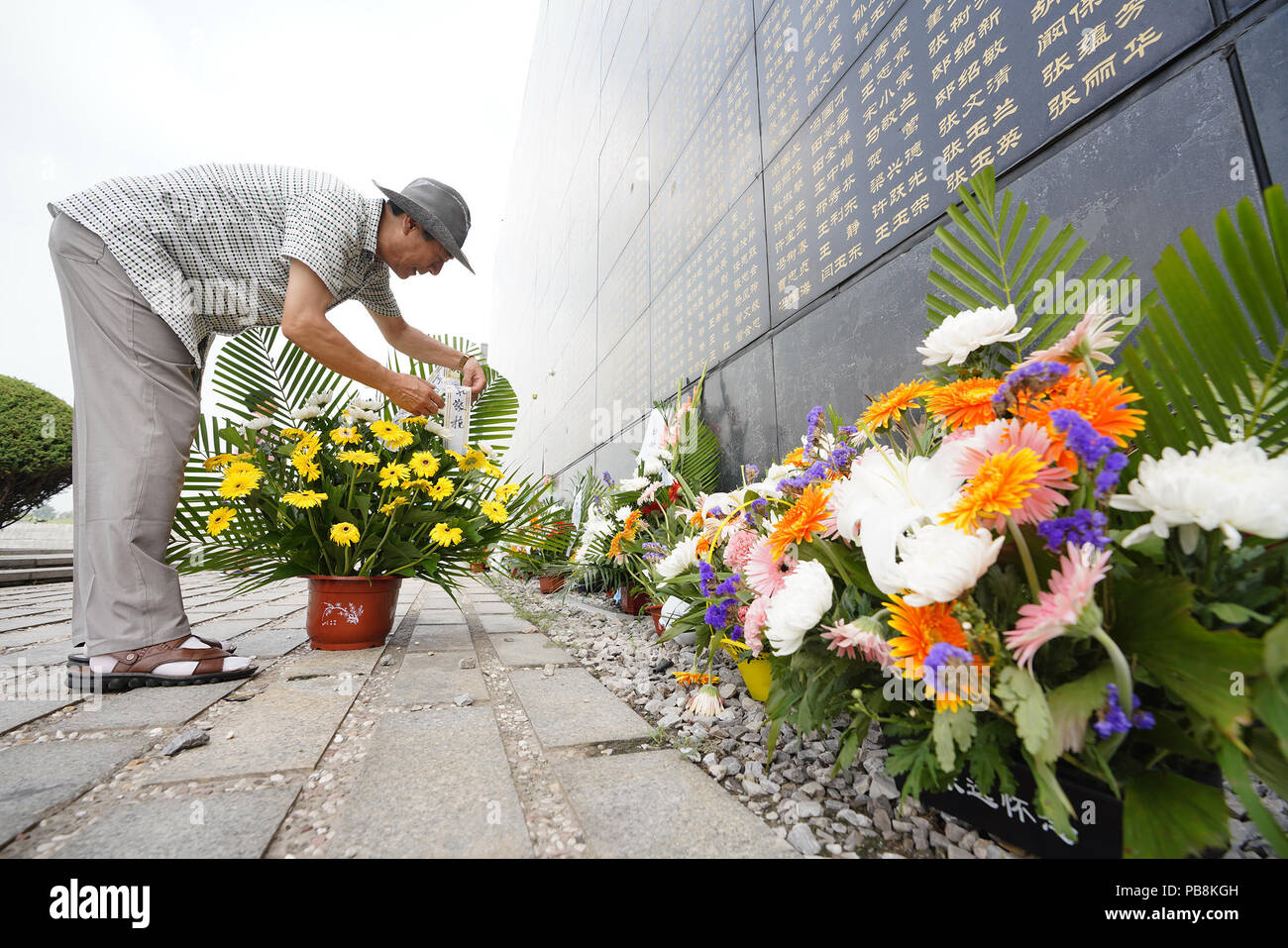 Tangshan. 27th July, 2018. A man arranges a flower basket in front of the memorial wall in Tangshan, north China's Hebei Province, July 27, 2018, one day before the 42nd anniversary of the 1976 Tangshan earthquake. Credit: Dong Jun/Xinhua/Alamy Live News Stock Photo