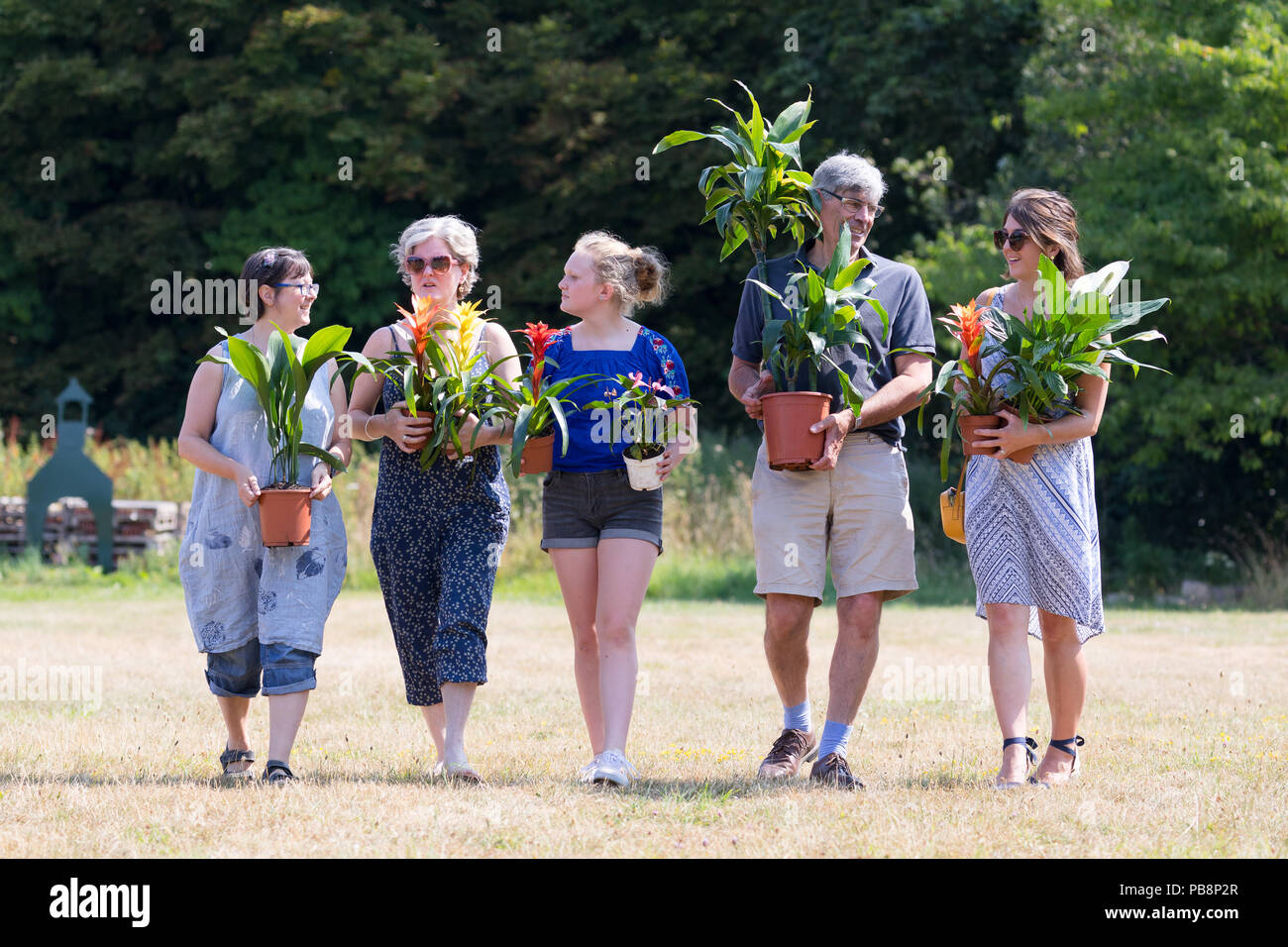 London, UK. 27th July 2018. People carry plants  from the RHS Hampton Court Palace Flower show plant adoption scheme at Moden Hall Park in London today. The innovative plant recycling scheme allows thousands of plants from the world's most prestigious flower shows to be rehomed, where members of the public are able to adopt a plant. Credit: Vickie Flores/Alamy Live News Stock Photo