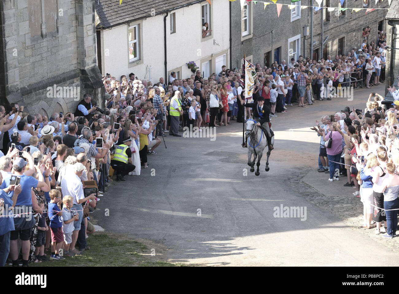 Langholm, Scotland, UK. 27th July, 2018.   Langholm Common Riding - 'Langholm's Great Day' Langholm Cornet Iain Little gallops up the Kirk Wynd ahead of his mounted supporters in Langholm, 'The Muckle Toon' has seen tradition upheld for over 250 years with the Annual Langholm Common Riding which takes place every year on the last Friday in July, This year falling on Friday 27th.    Credit: Rob Gray/Alamy Live News Stock Photo