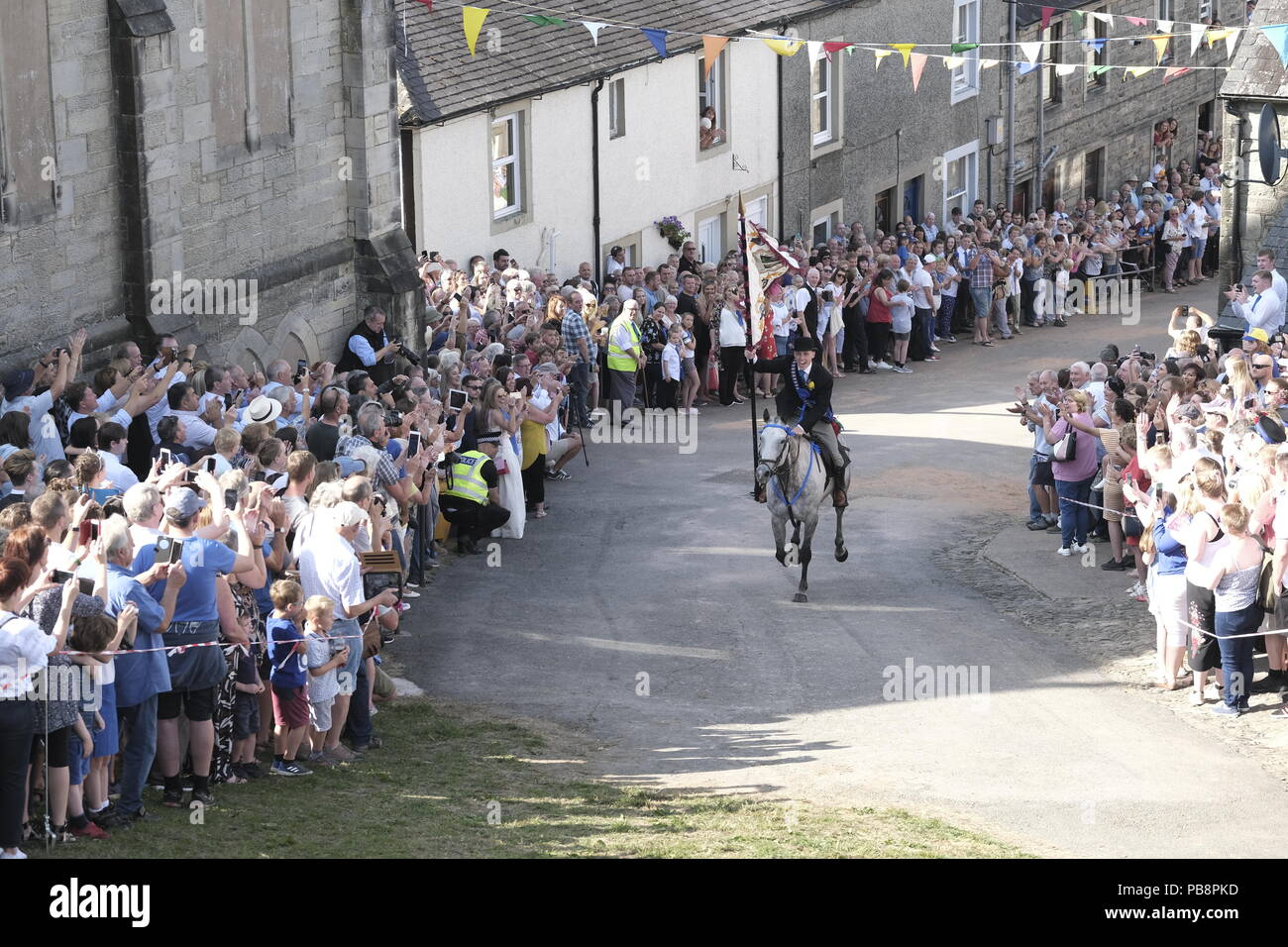 Langholm, Scotland, UK. 27th July, 2018.    Langholm Common Riding - 'Langholm's Great Day' Langholm Cornet Iain Little gallops up the Kirk Wynd ahead of his mounted supporters in Langholm, 'The Muckle Toon' has seen tradition upheld for over 250 years with the Annual Langholm Common Riding which takes place every year on the last Friday in July, This year falling on Friday 27th.   Credit: Rob Gray/Alamy Live News Stock Photo