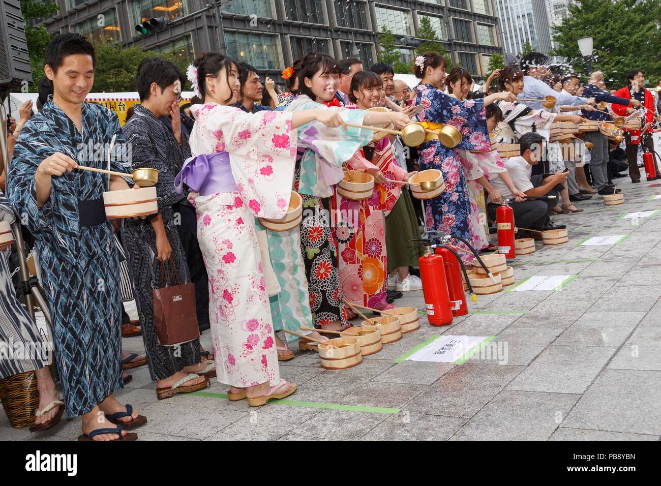 People wearing yukata (casual kimono) splash water onto the ground during  the ''Marunouchi de Uchimizu'' event in front of Tokyo Station on July 27,  2018, Tokyo, Japan. The Uchimizu (water sprinkling) aims