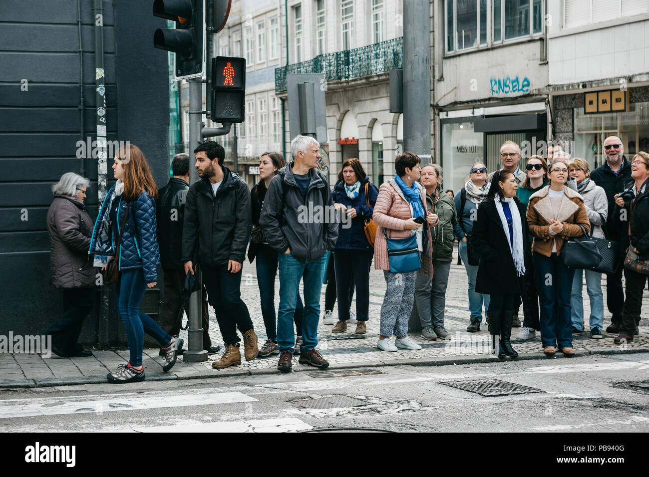 Portugal, Porto, May 05, 2018 A crowd of people stands on a red traffic light and wait for the