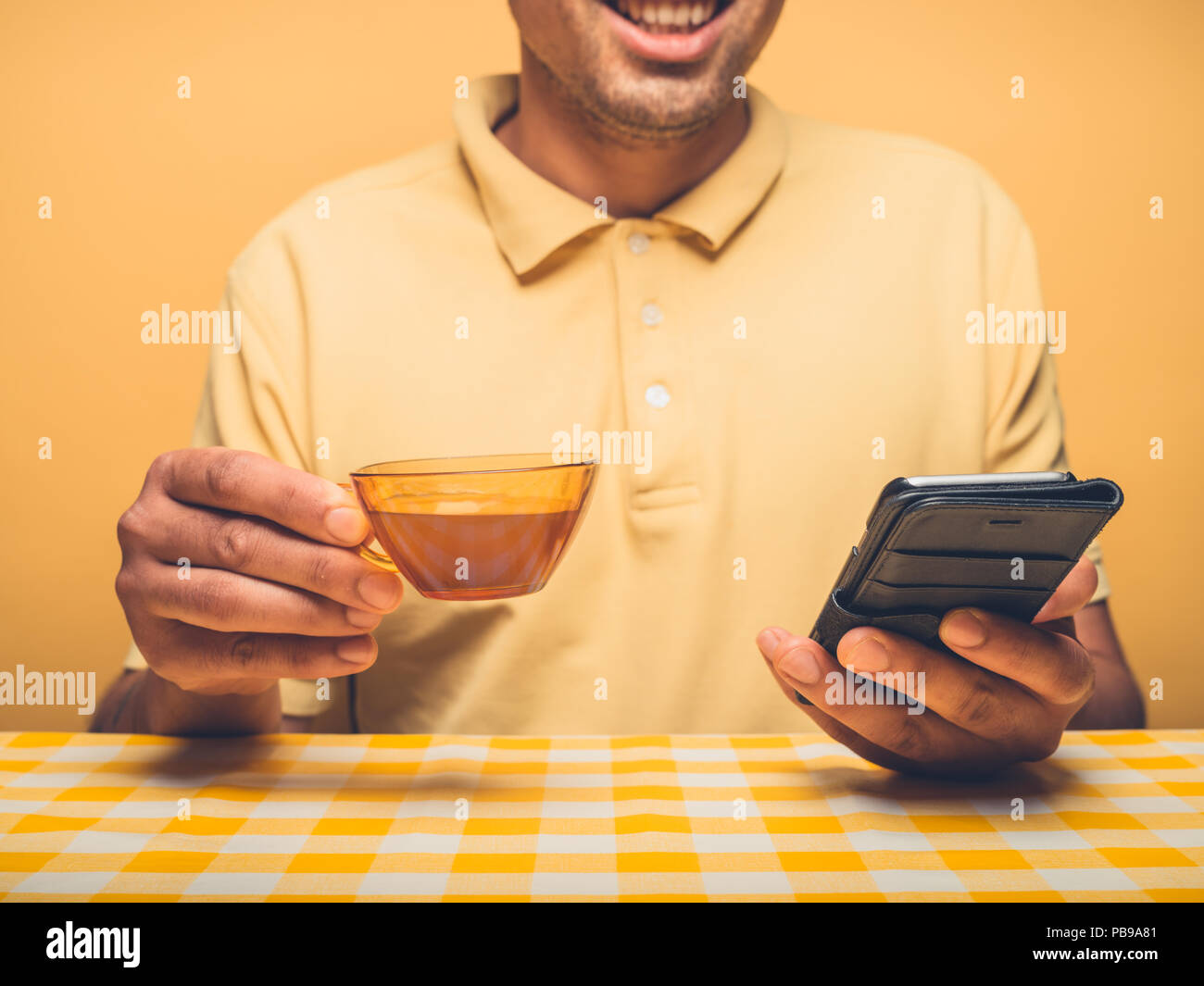 A young hipster man is drinking coffee and using smartphone Stock Photo