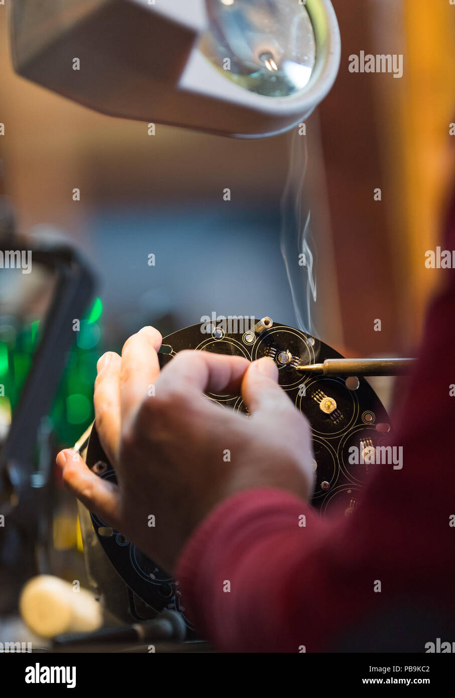 Young man with safety glasses repairing motheboard with soldering iron Stock Photo