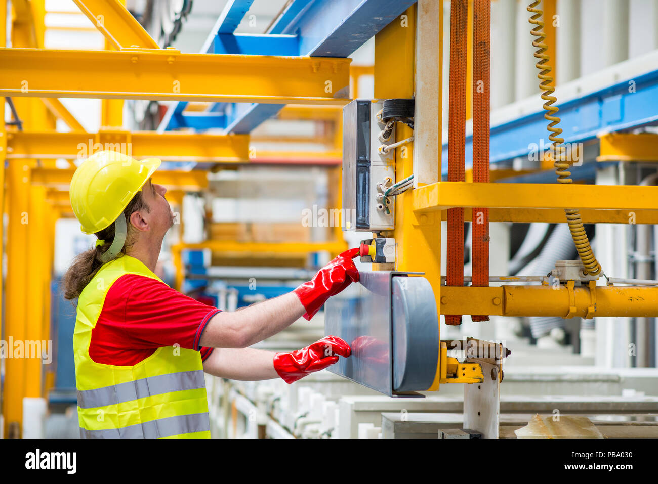 Factory worker pressing a red button. Factory worker starting a machine Stock Photo