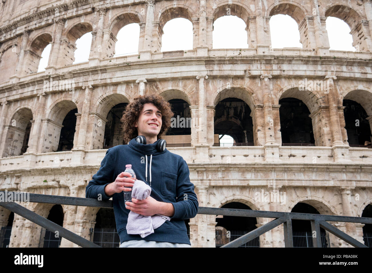 Handsome young guy relaxing after training in front of Colosseum in Rome Stock Photo