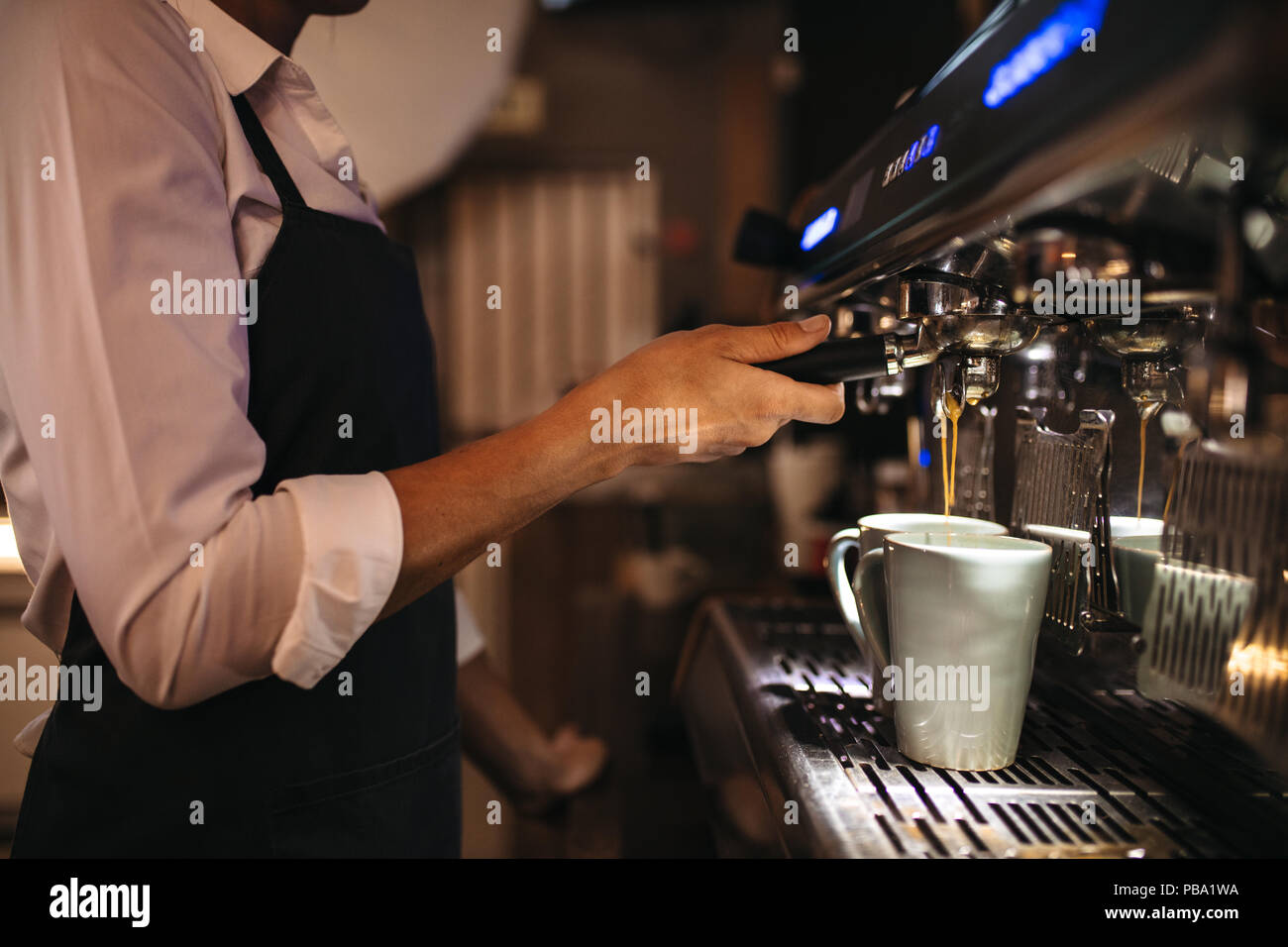 Cropped shot of barista using a coffee maker to prepare a cup of coffee. Female cafe worker making a coffee. Stock Photo