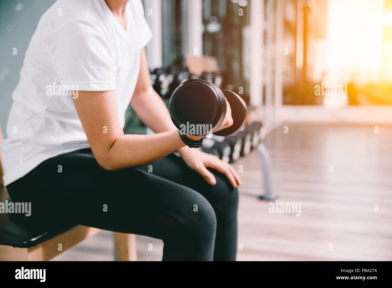 closeup slim healthy woman lifting dumbbell personal weight training in sport club casual wear Stock Photo