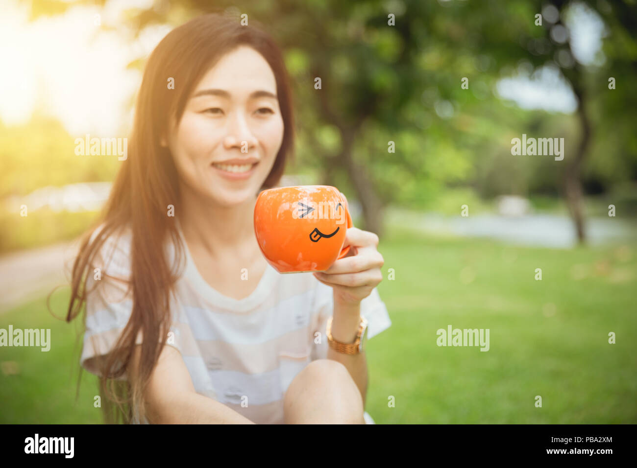 Girl teen hand holding smile mug for hot drink morning in the park holiday Stock Photo