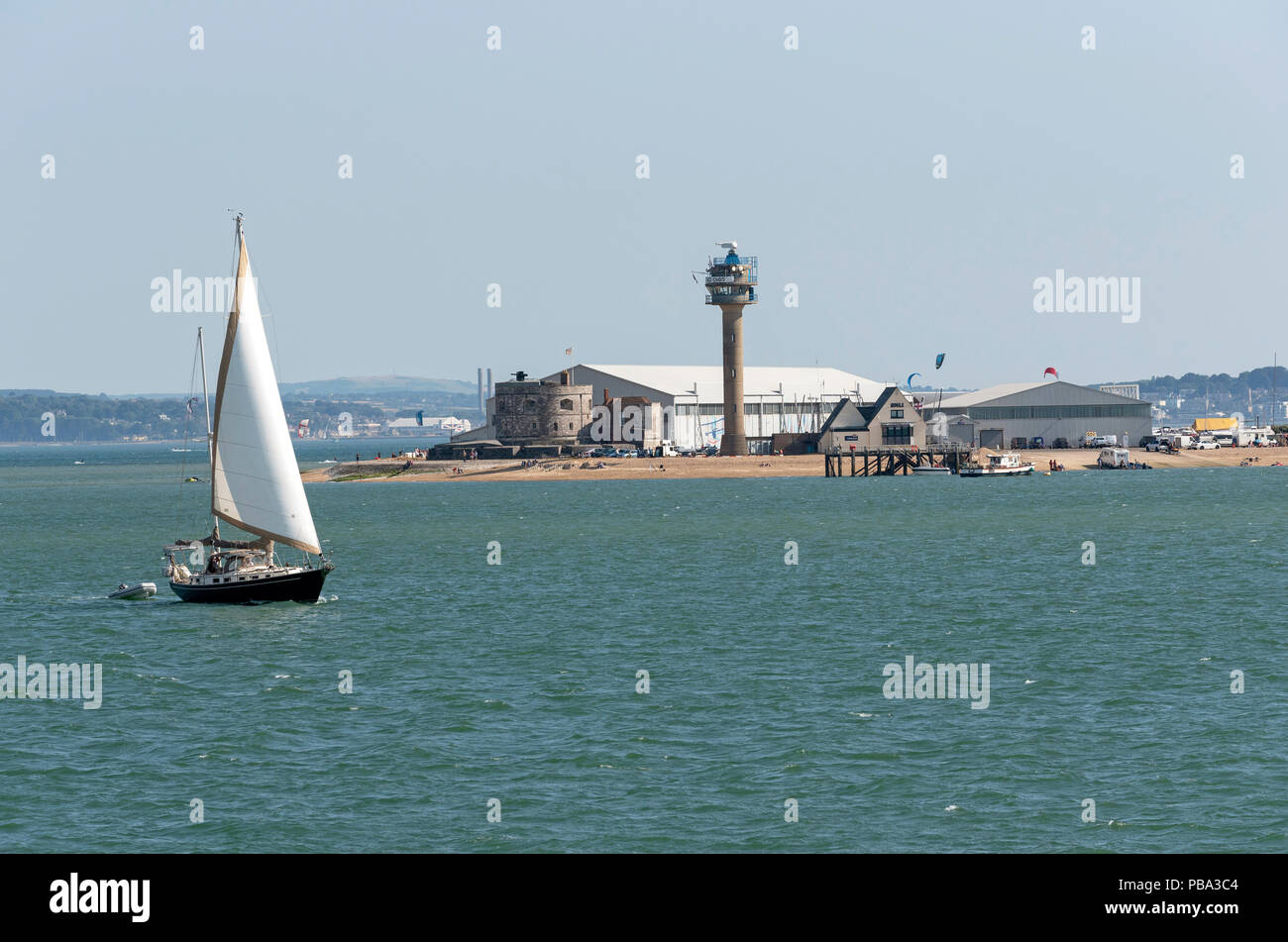 Sailing boat passing Calshot Activities centre on the shores of the
