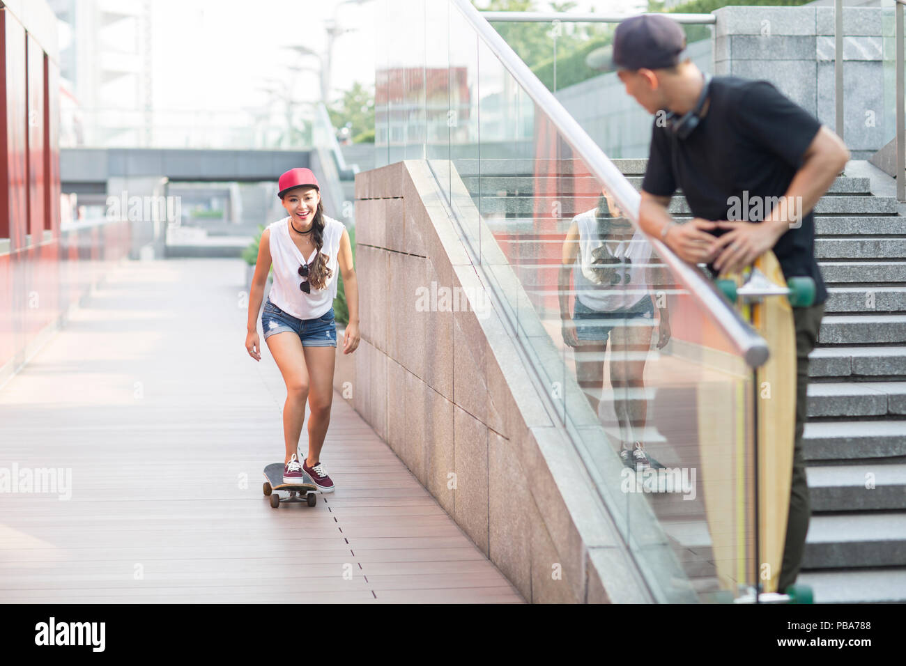 Cheerful young Chinese couple skateboarding Stock Photo Alamy