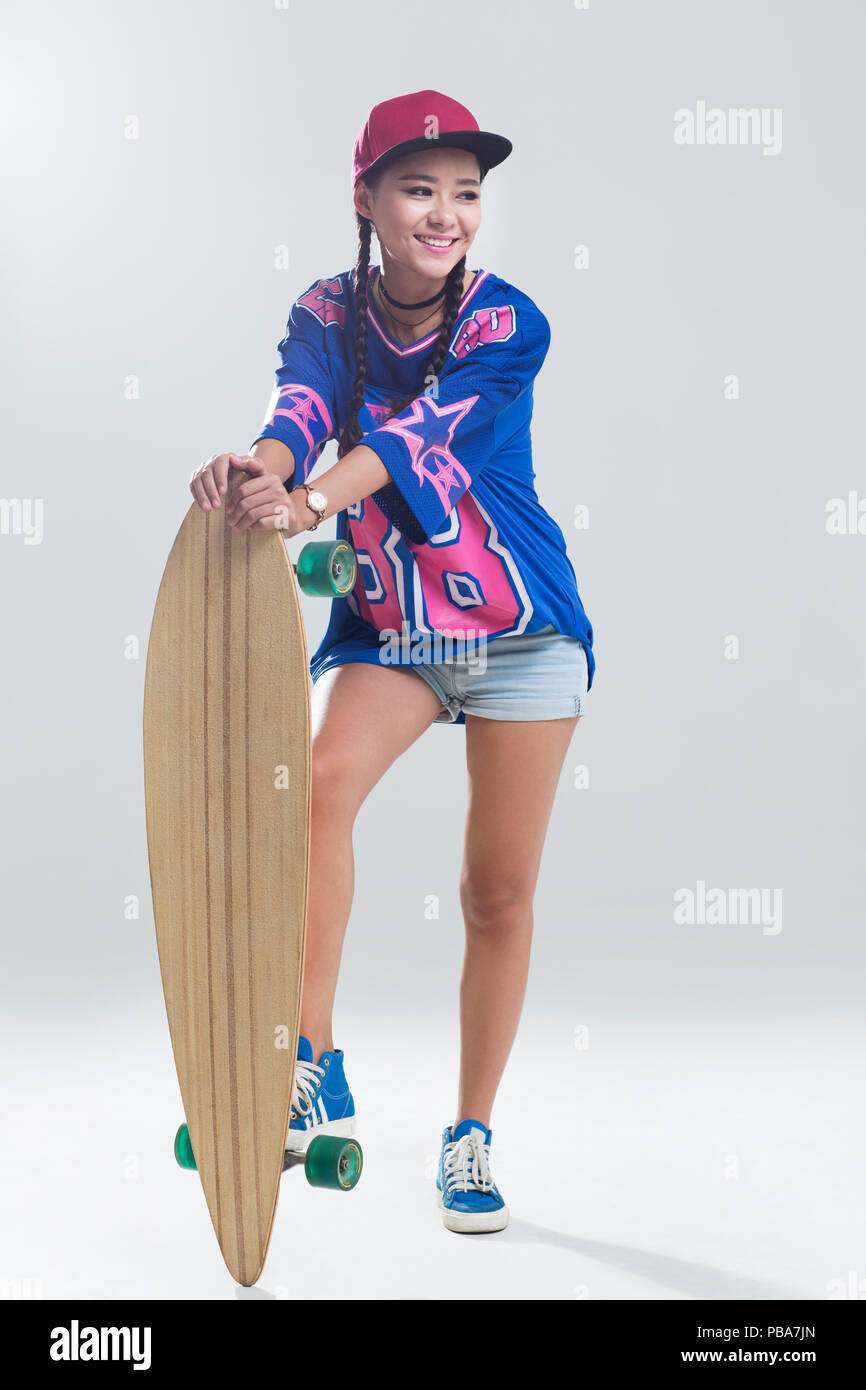 Cheerful young Chinese woman with skateboard Stock Photo
