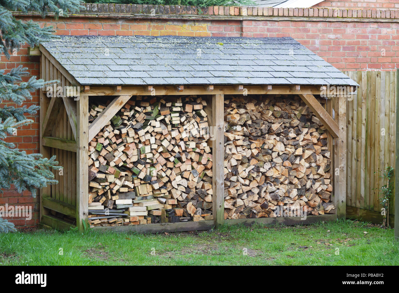 Large log store filled with firewood, timber construction with a slate roof Stock Photo