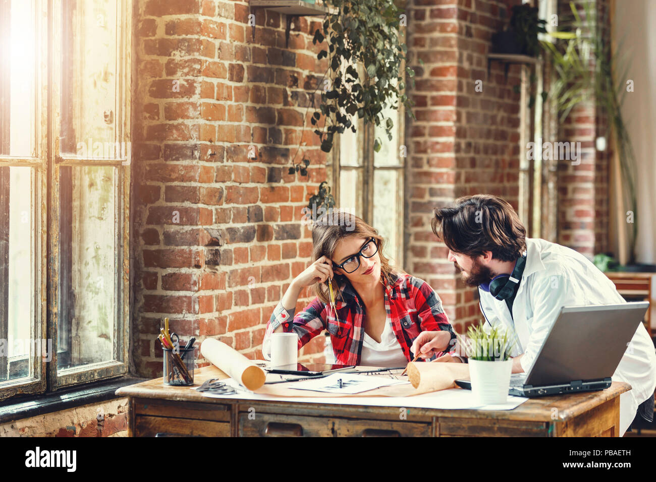 Two ambitious architects discussing construction project in loft modern office, they using laptop Stock Photo
