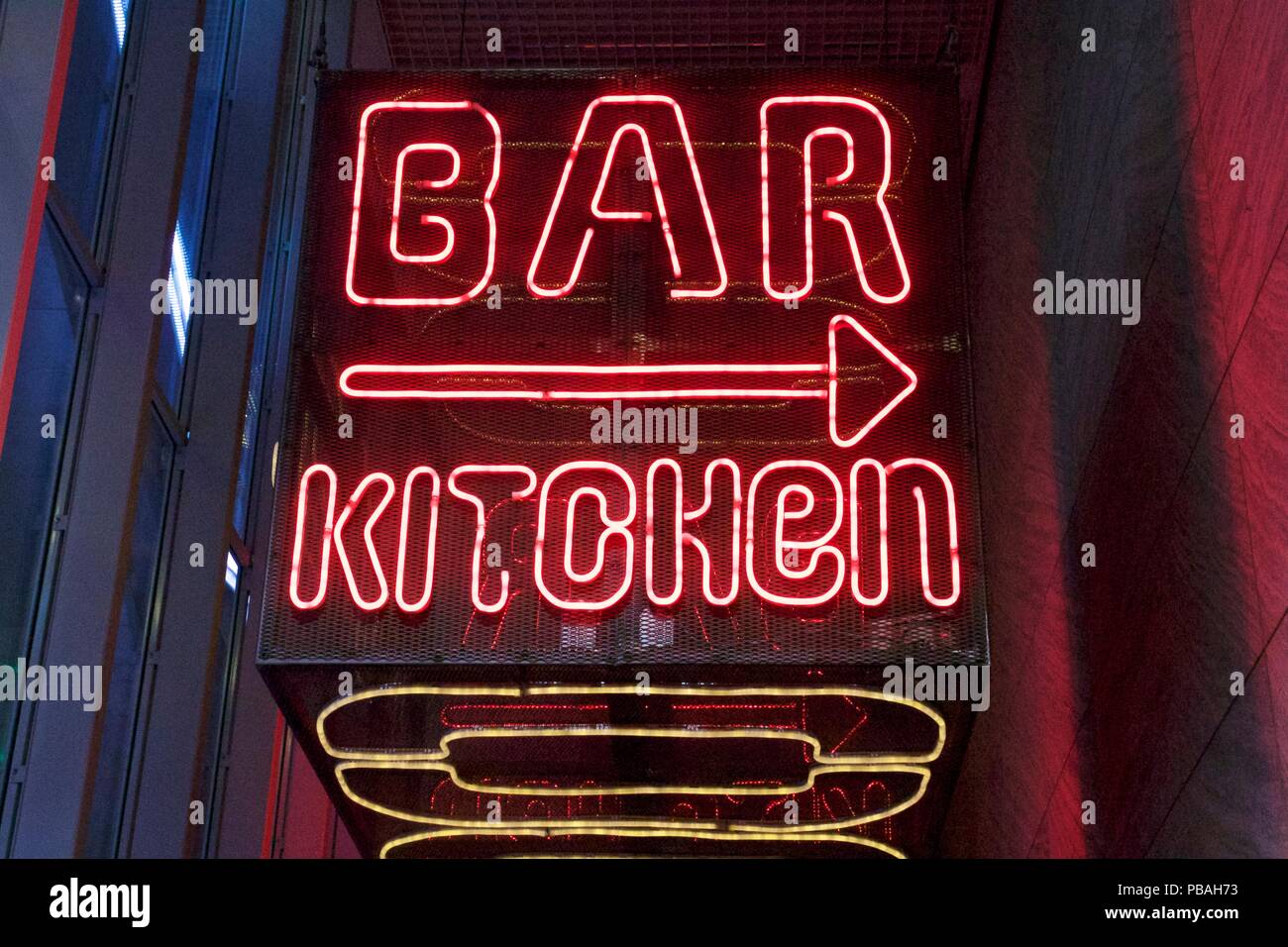 Red neon sign saying Bar Kitchen with an arrow pointing to the right Stock Photo