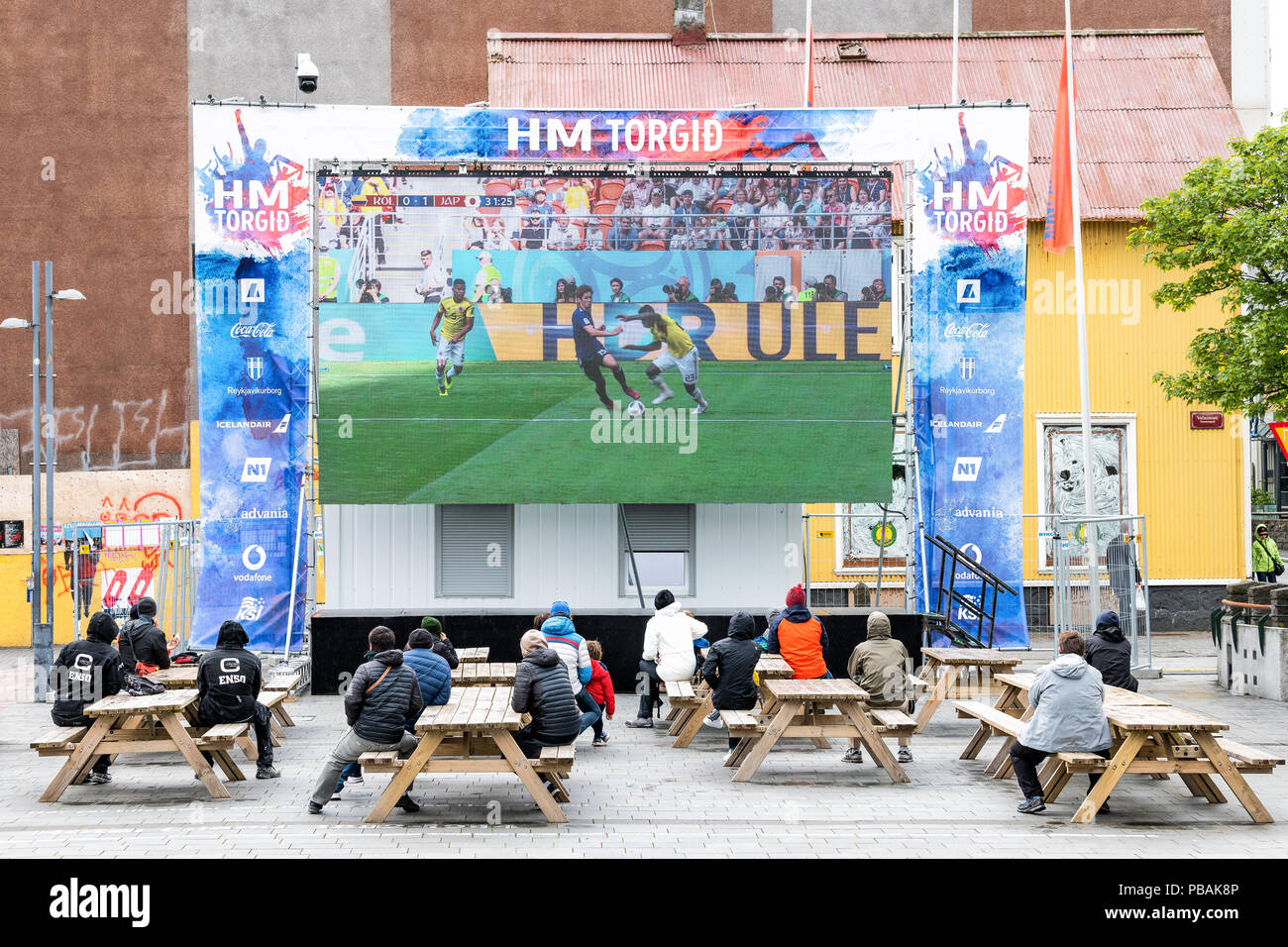 Reykjavik, Iceland - June 19, 2018: Ingolfur Ingolfstorg Square with man walking with signs for HM Torgid, large screen tv television, people watching Stock Photo