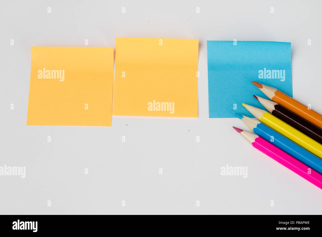 Pencil and sticky notes on a white table. Office accessories for saving notes. White background. Stock Photo