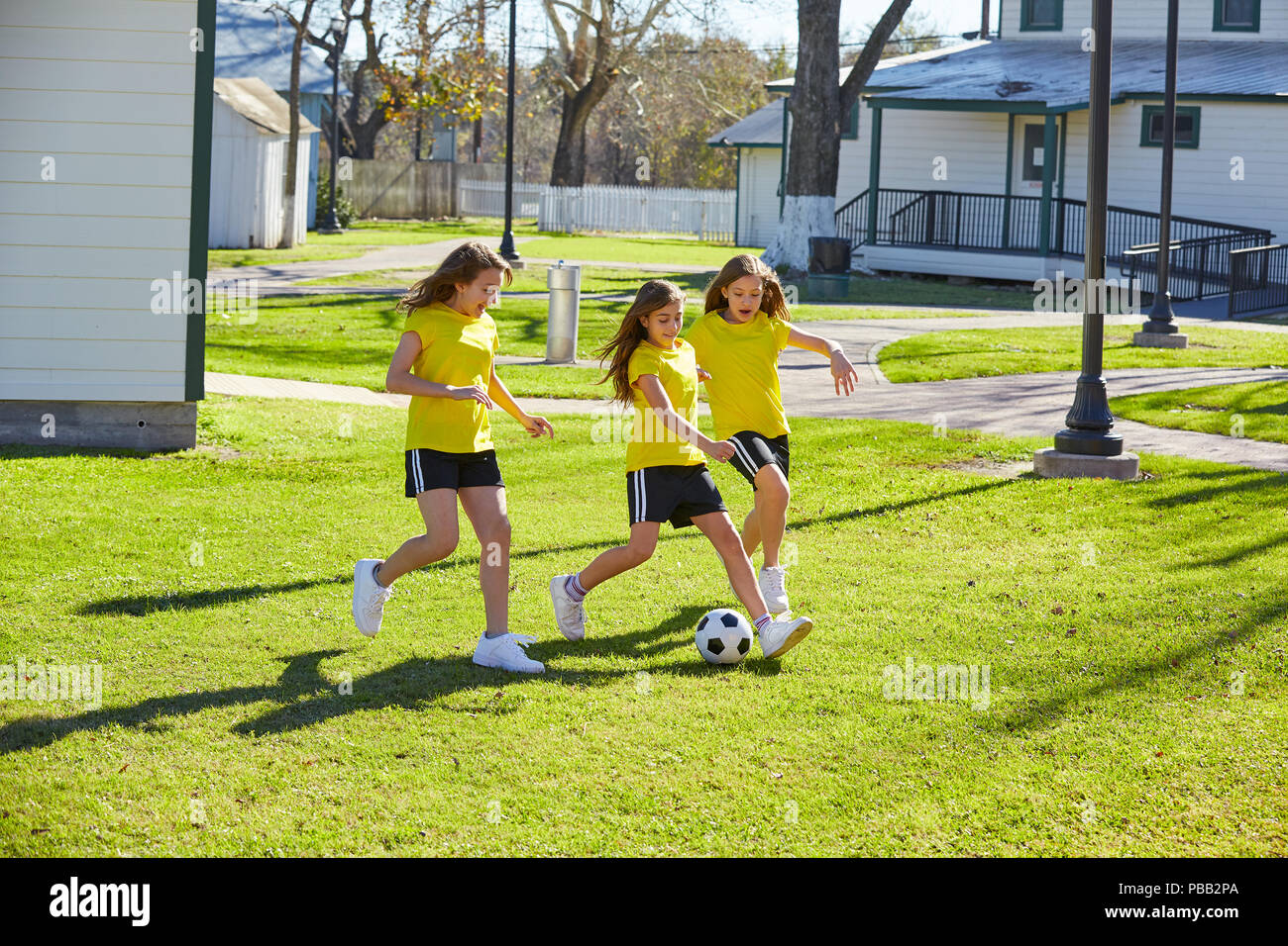 Friend girls teens playing football soccer in a park turf grass Stock Photo