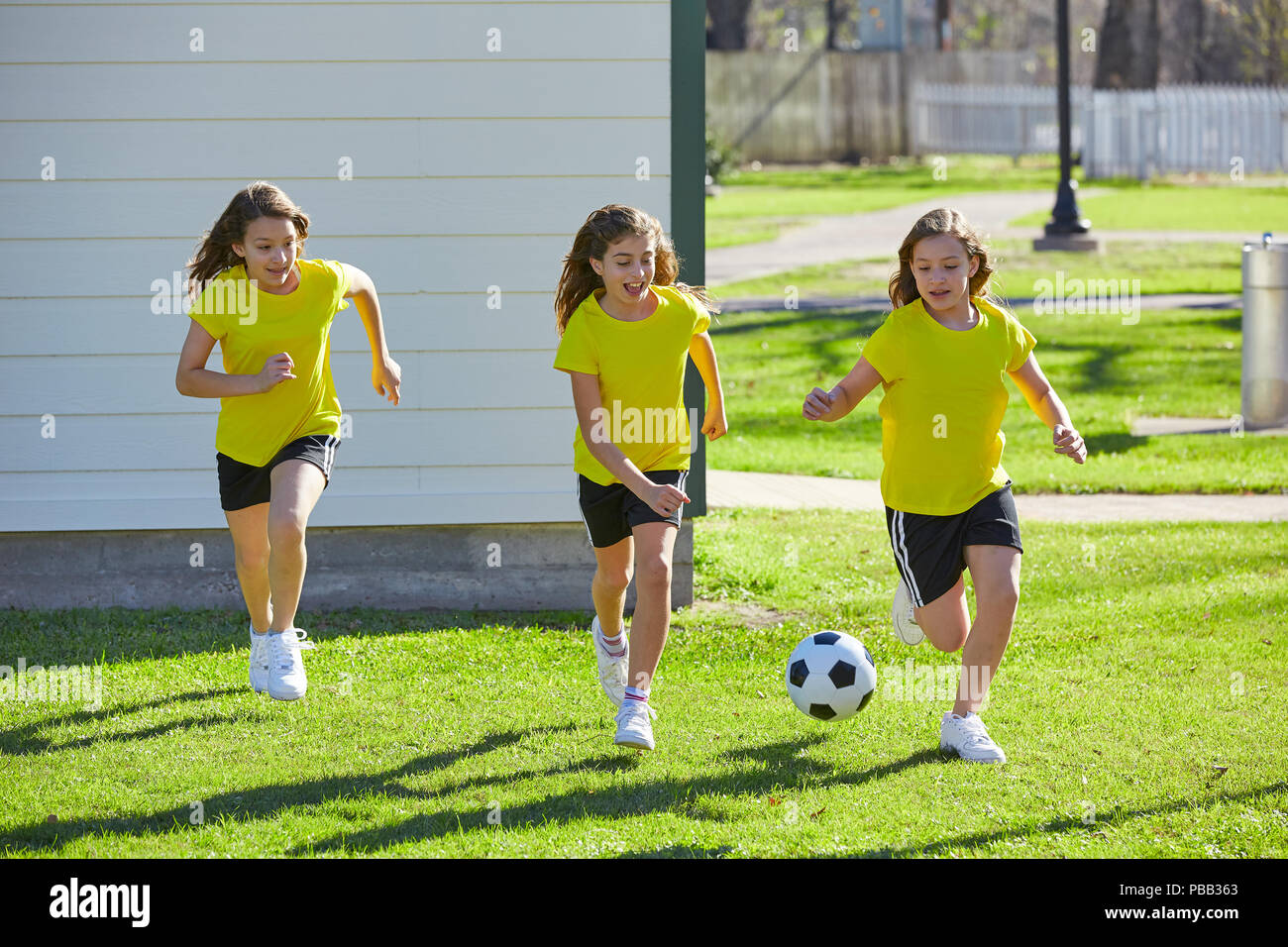 Friend girls teens playing football soccer in a park turf grass Stock Photo