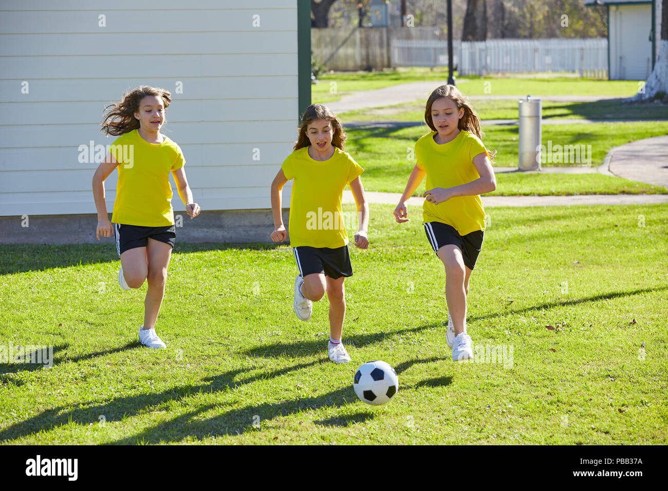 Friend girls teens playing football soccer in a park turf grass Stock Photo
