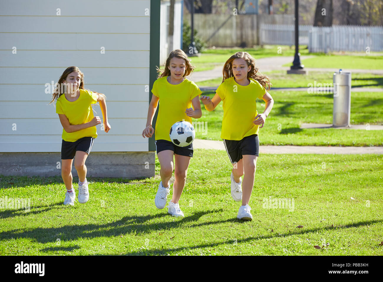 Friend girls teens playing football soccer in a park turf grass Stock Photo