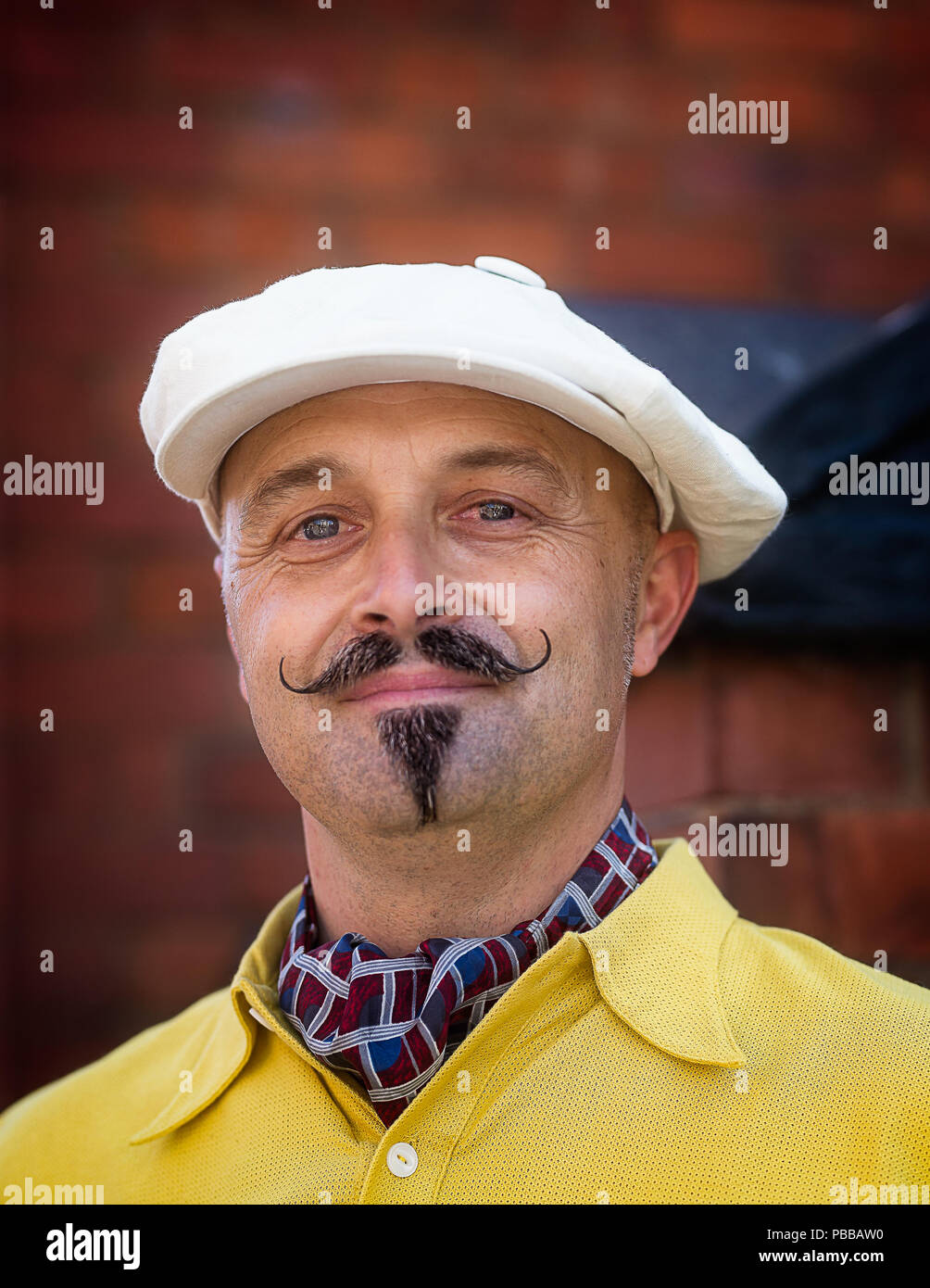Portrait close up of isolated handsome man with waxed moustache & newsboy cap looking dapper in 1940s dress, Black Country Museum 1940's WWII event. Stock Photo