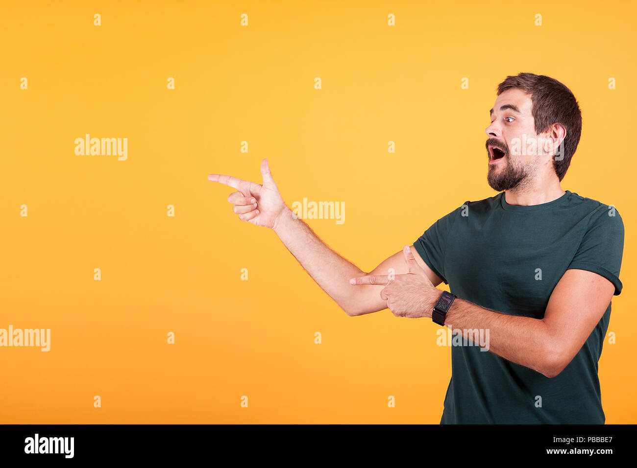 Enthusiasm and expressive man pointing at the copyspace available for your text, promo or advertising. The male is surprised and happy. Orange background Stock Photo