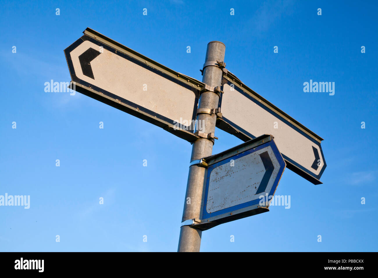 Signpost with three blank signboards against blue sky low viewpoint copy space. Decision concept. Stock Photo