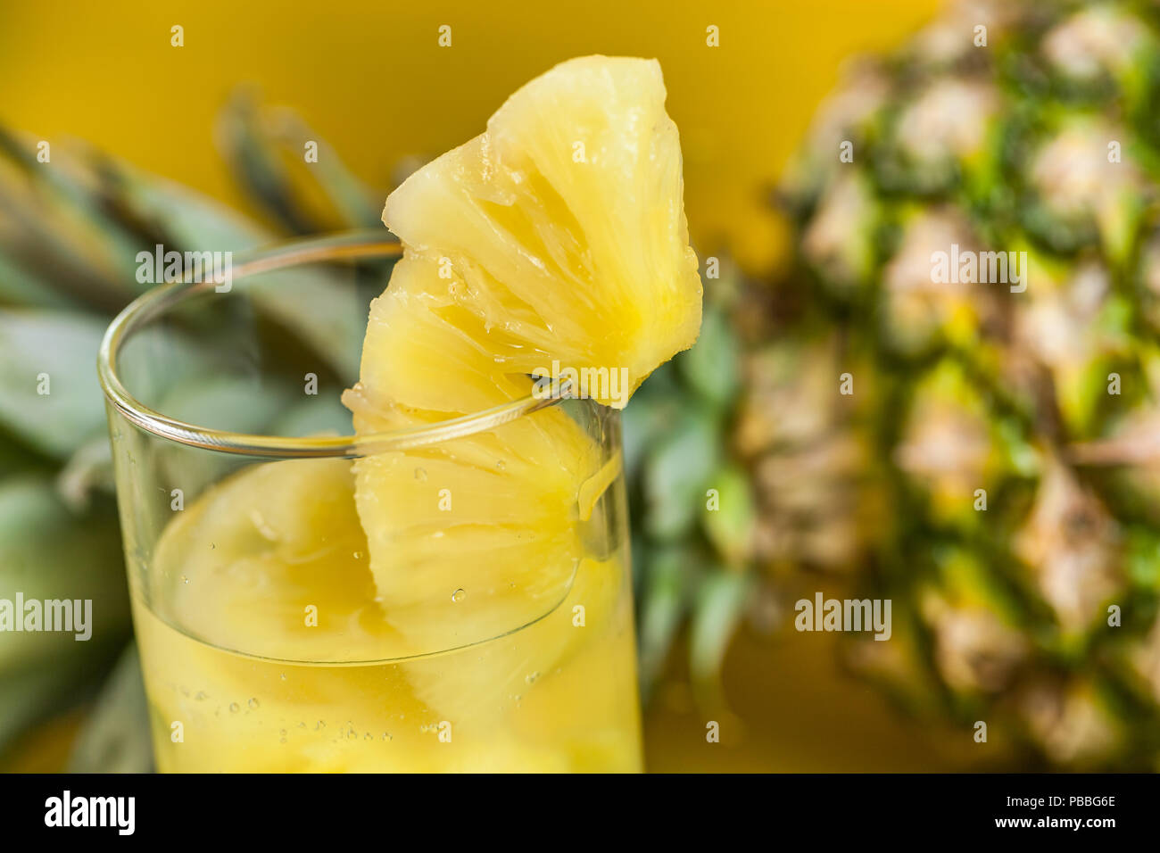 Ripe pineapple and juice in a glass on a yellow wooden background Stock ...