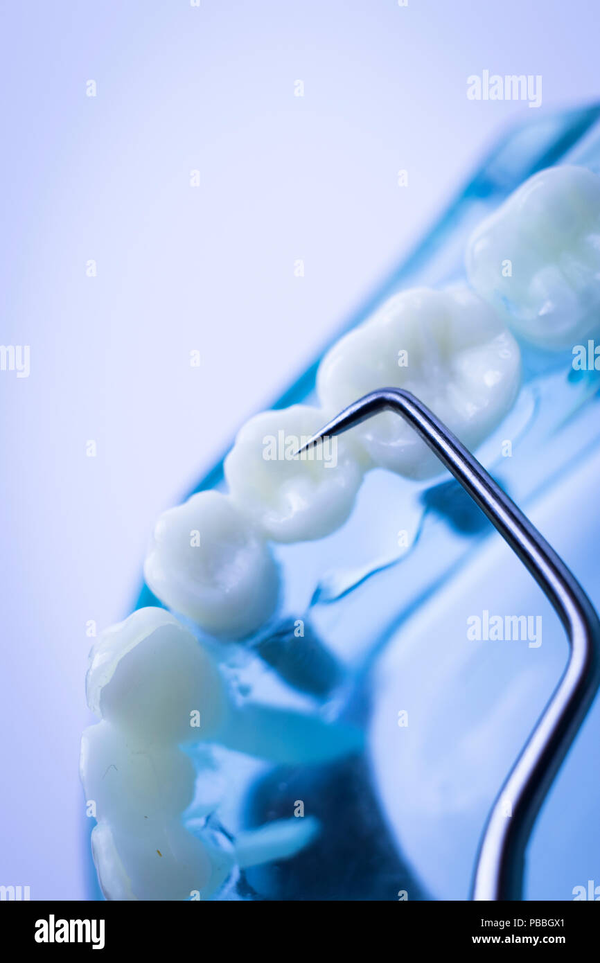 Dentist cleaning teeth with titanium metal tooth pick instrument to