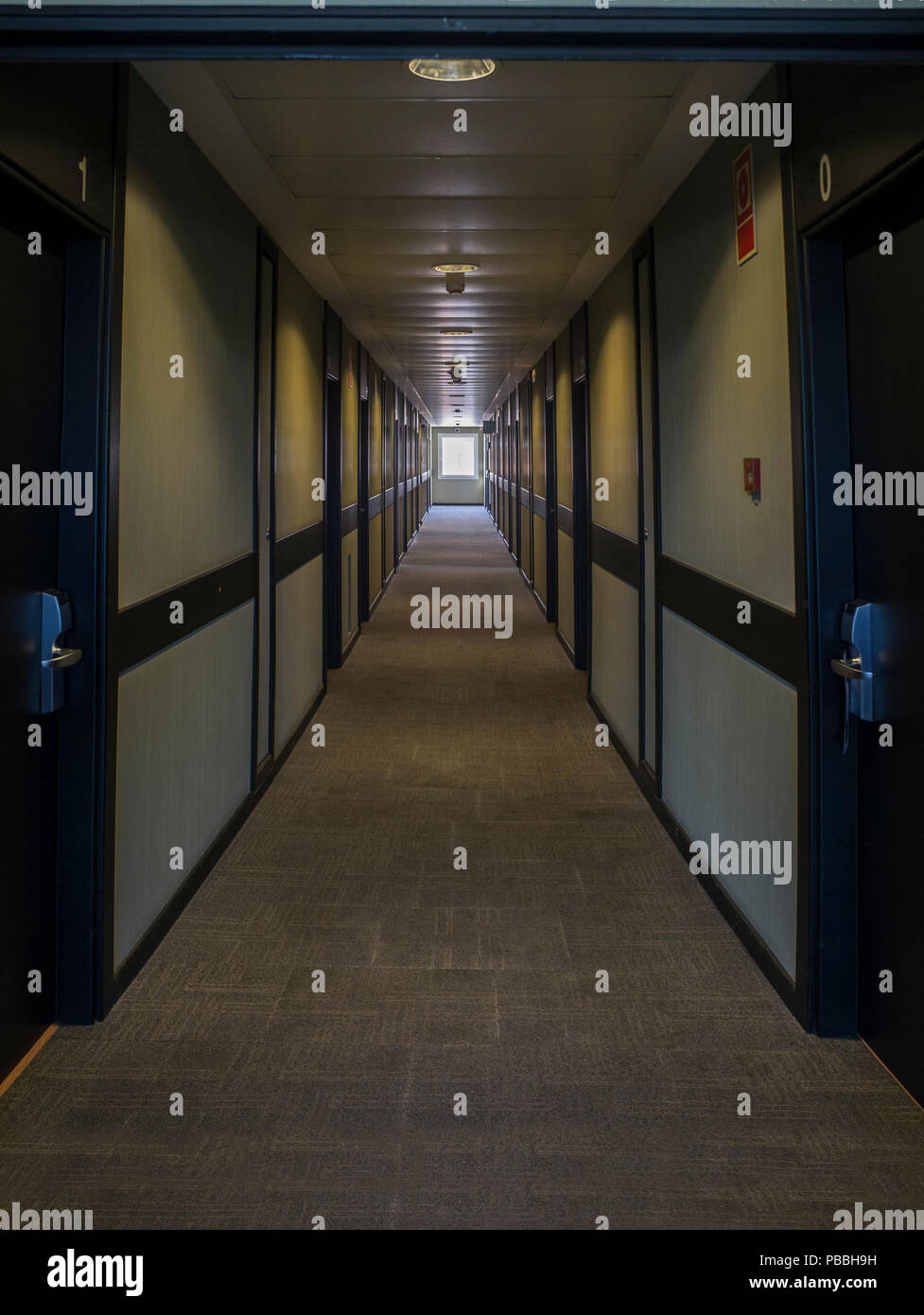 Dark hotel corridor illuminated by natural light. A wide window can be seen in the background Stock Photo