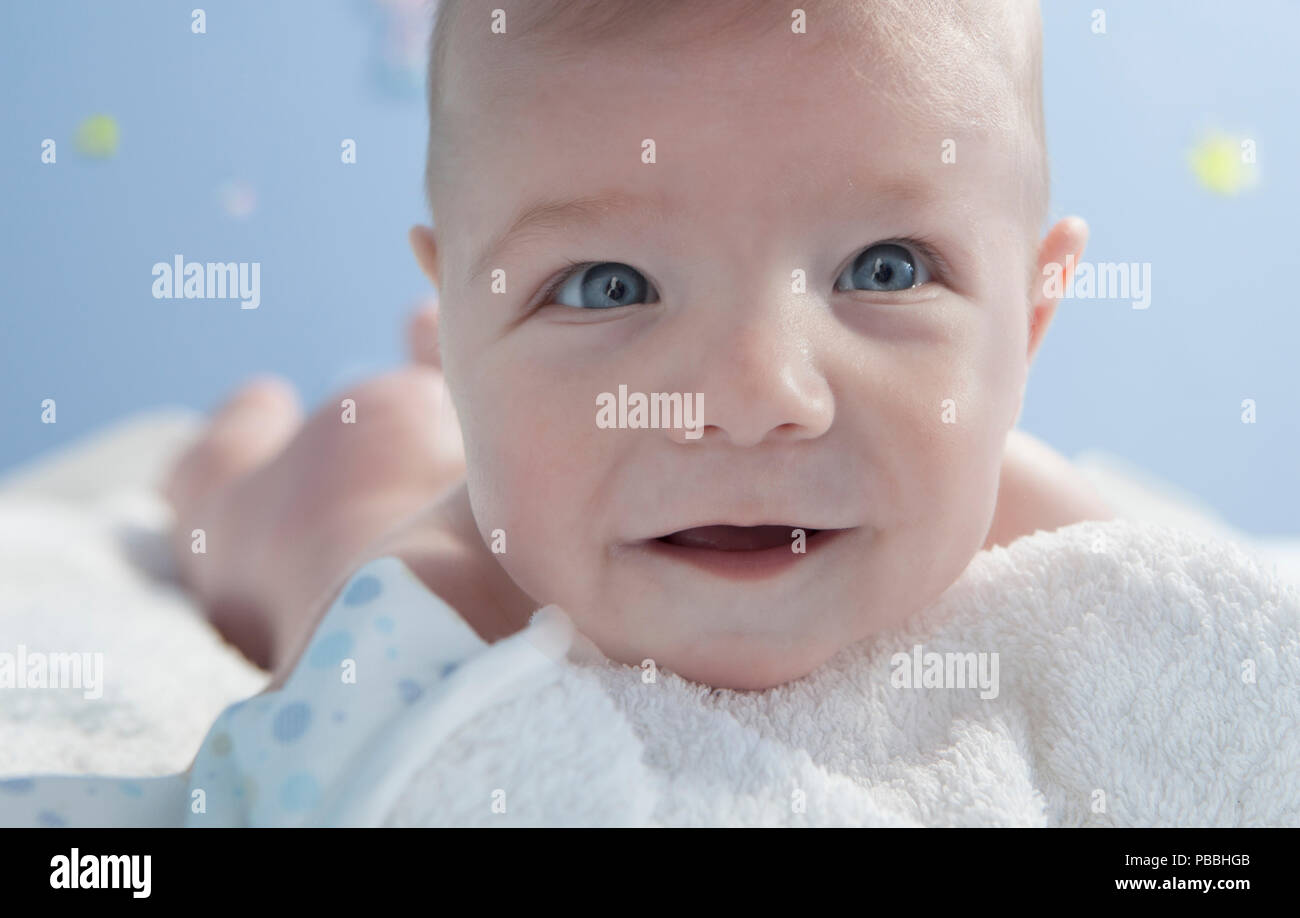 Cute happy three months baby after bath in bed at home. He is face down