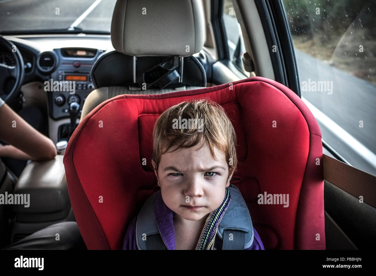 Handsome baby boy gets angry on car seat. Surviving a long car journey with children concept Stock Photo
