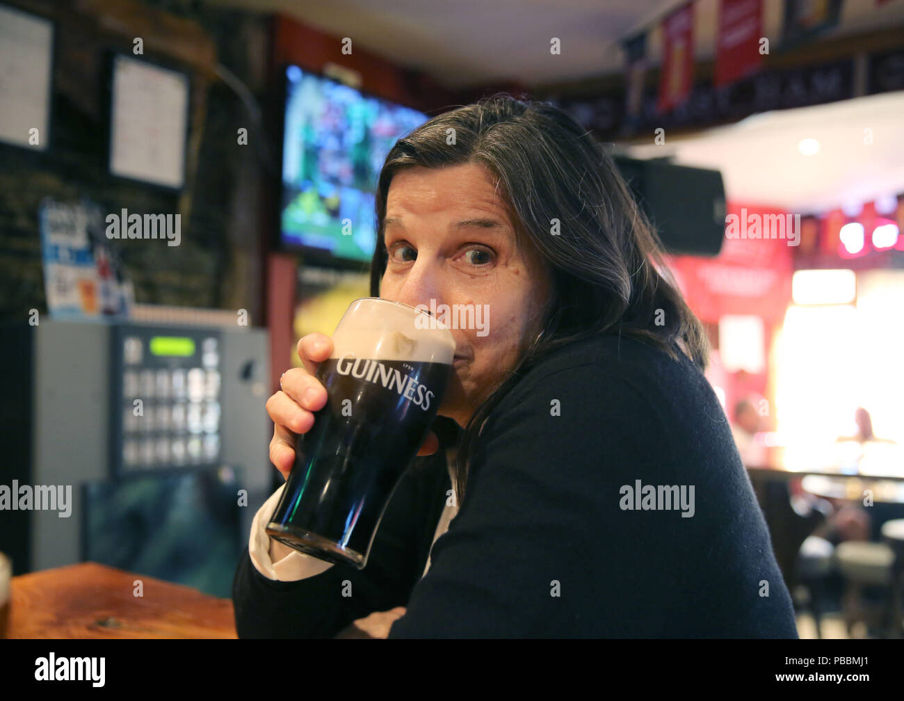 Senior woman drinks a pint of Guinness in an Irish pub. Stock Photo
