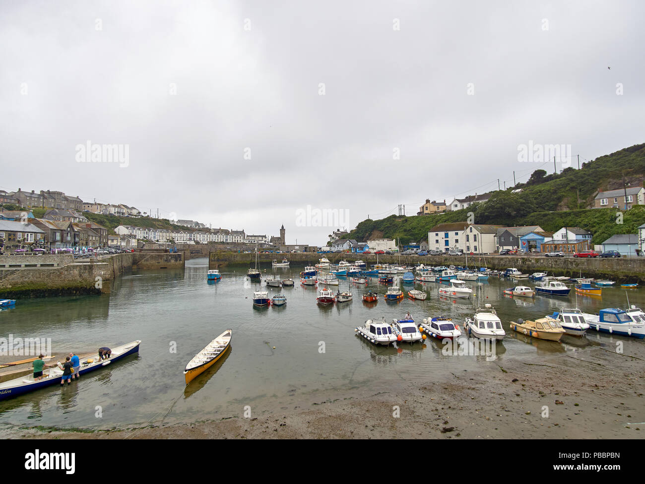 Porthleven Harbour, Cornwall, with a group of rowers preparing for a late-afternoon outing in a Cornish Pilot Gig Stock Photo