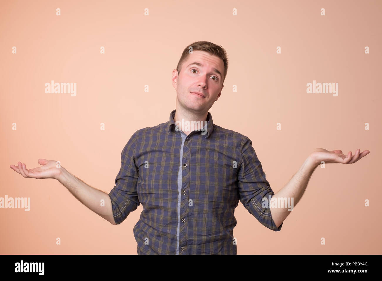 Studio portrait of confused handsome guy showing I have no idea gesture. Stock Photo