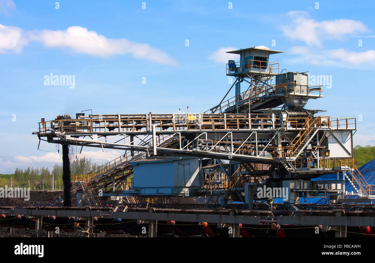 Large conveyor belt carrying coal and emptying onto a huge pile. Stock Photo