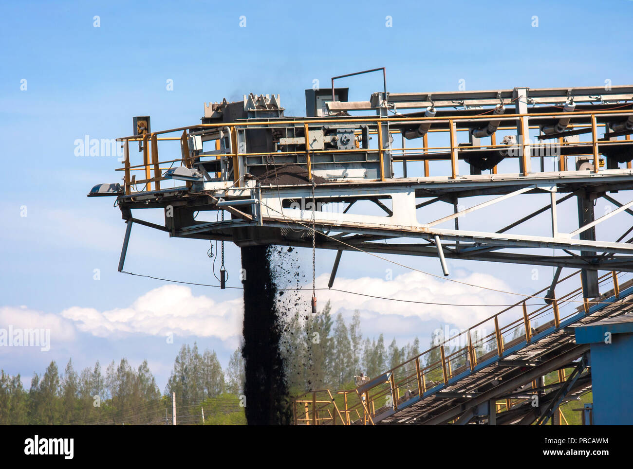 Large conveyor belt carrying coal and emptying onto a huge pile. Stock Photo