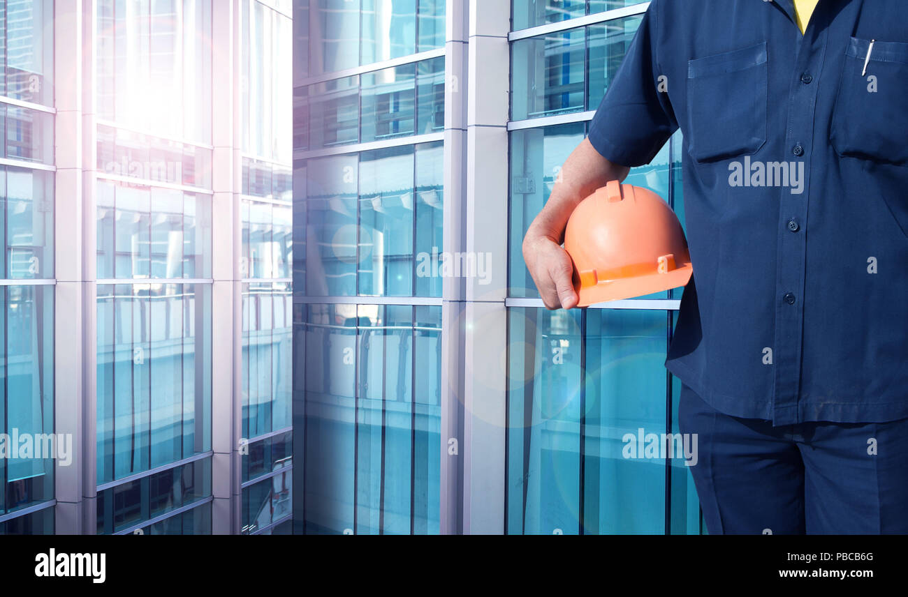 engineer holding orange helmet for workers security on office buildings in blue color tone Stock Photo