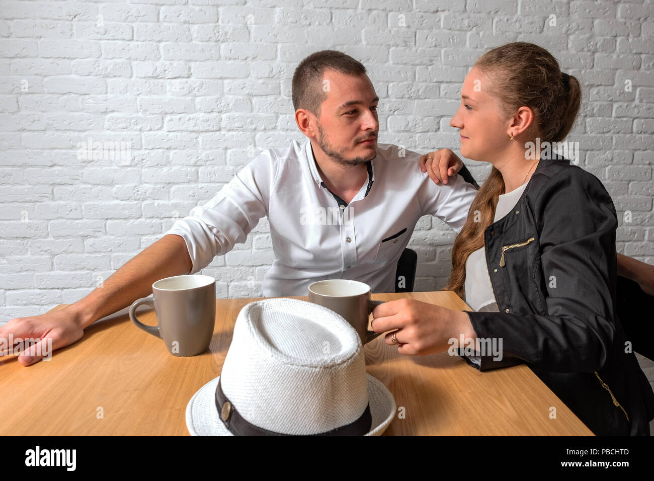 The Girl And The Guy In Cafe At A Table Talk The Loving Couple Sits In